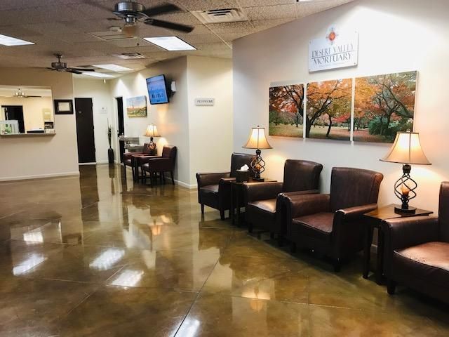 Quiet lobby with brown leather chairs, lamps, artwork, polished floor, and reception desk in the background