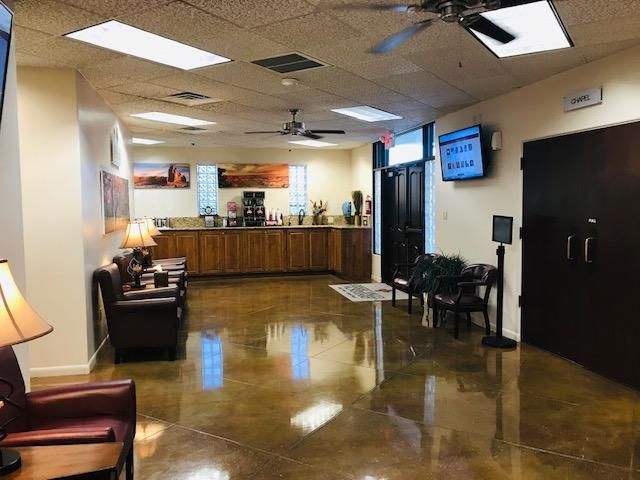 Bright lobby with polished floor, waiting chairs, reception desk, and wall-mounted TV.