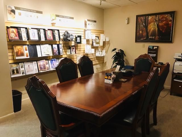 Office conference room with a wooden table, black chairs, brochure racks, and framed wall art.