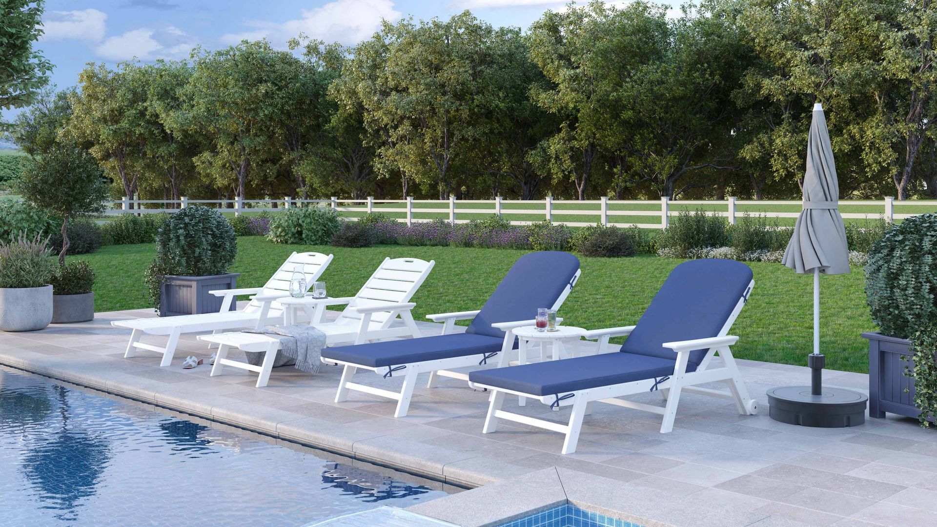 Poolside scene: White lounge chairs with blue cushions, side tables, umbrella, and pool with trees in the background.