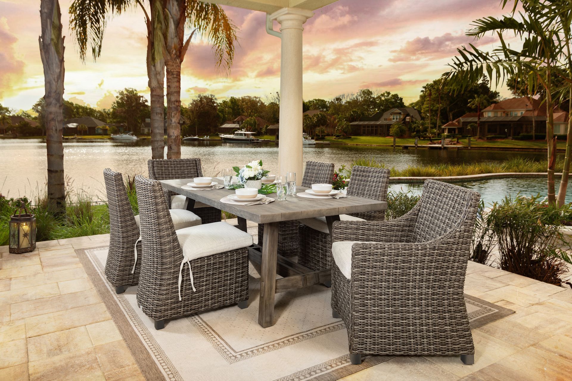 A patio with a table and chairs next to a body of water.