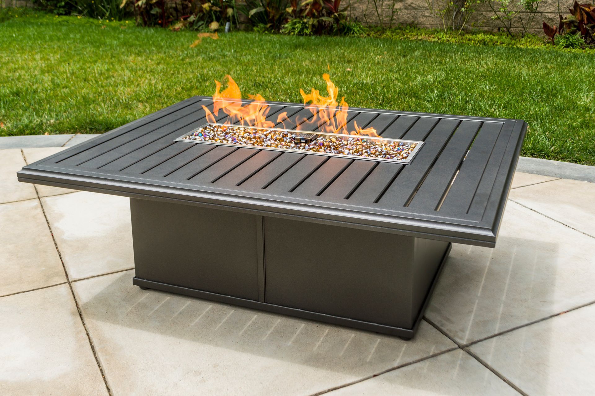 A fire pit on a patio with flames coming out of it