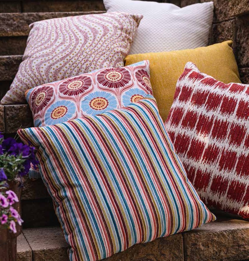 A bunch of colorful pillows are sitting on a bench