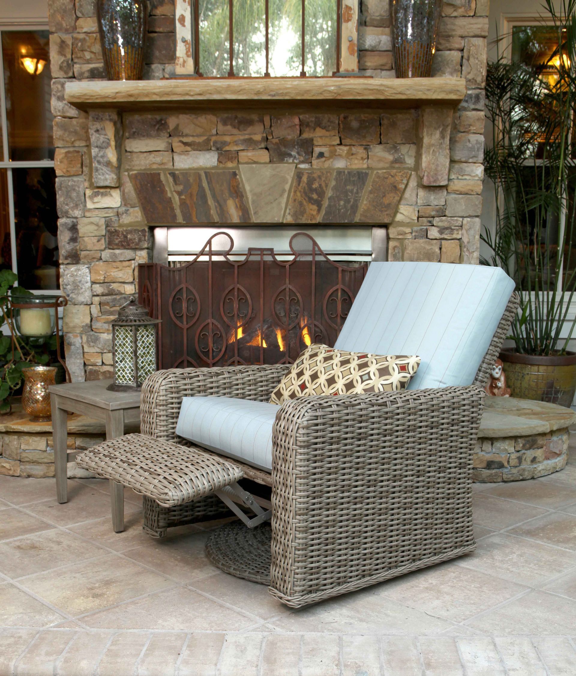 A wicker chair is sitting in front of a stone fireplace