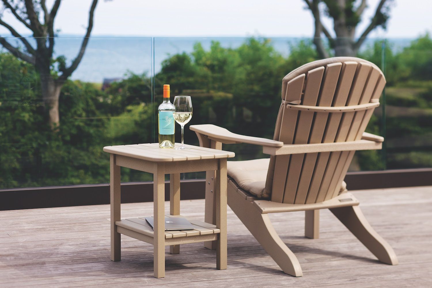 A chair and a table with a bottle of wine and two glasses on it.
