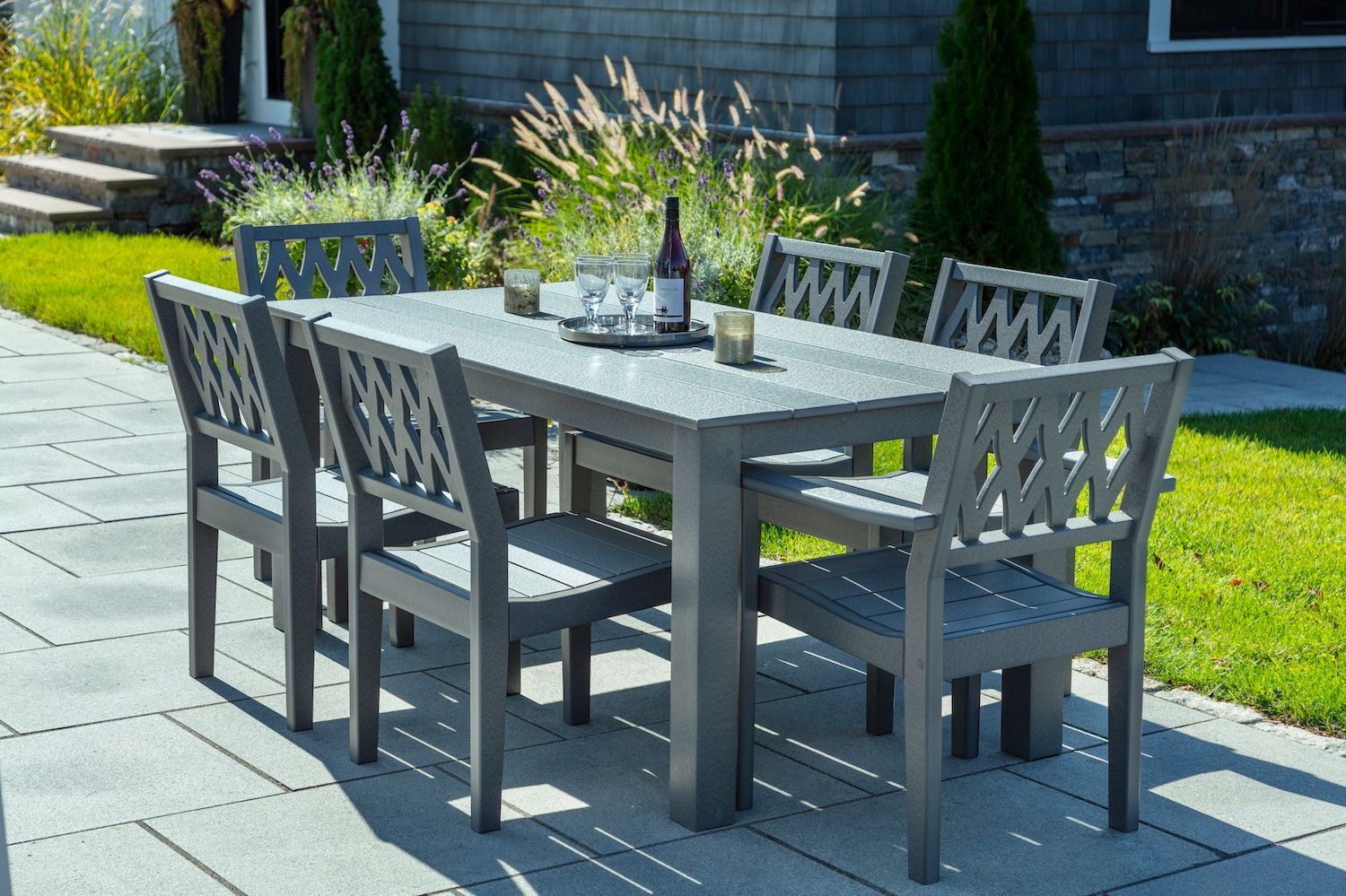 A patio with a table and chairs and a bottle of wine on it.