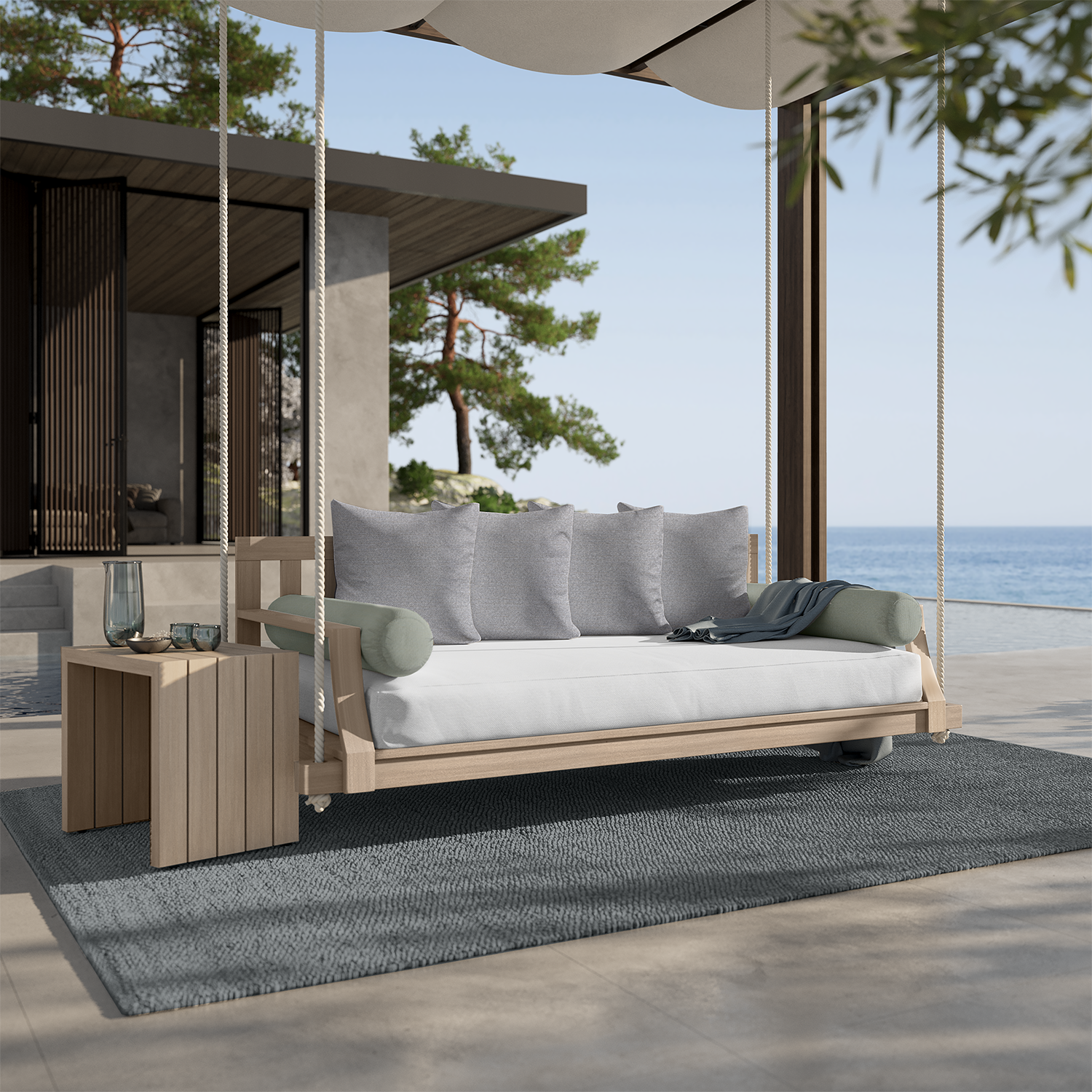 Outdoor swing with pillows, side table, rug. Overlooks ocean.