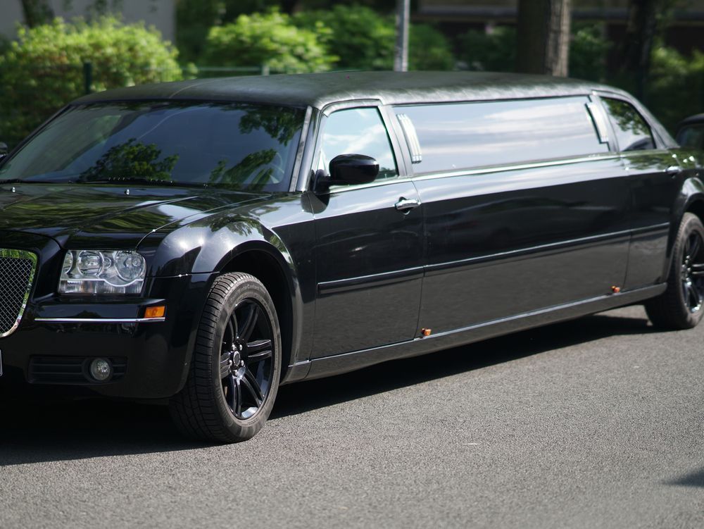 Black stretch limousine parked on a street with trees in the background