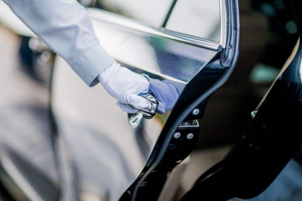 Gloved hand opening a black car door in a close-up view