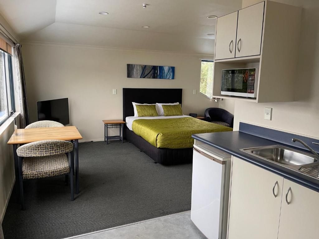 A hotel room with a bed , table , chairs and a kitchen.