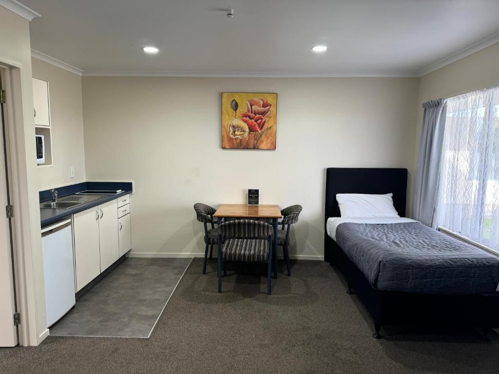 A hotel room with a single bed , table and chairs.
