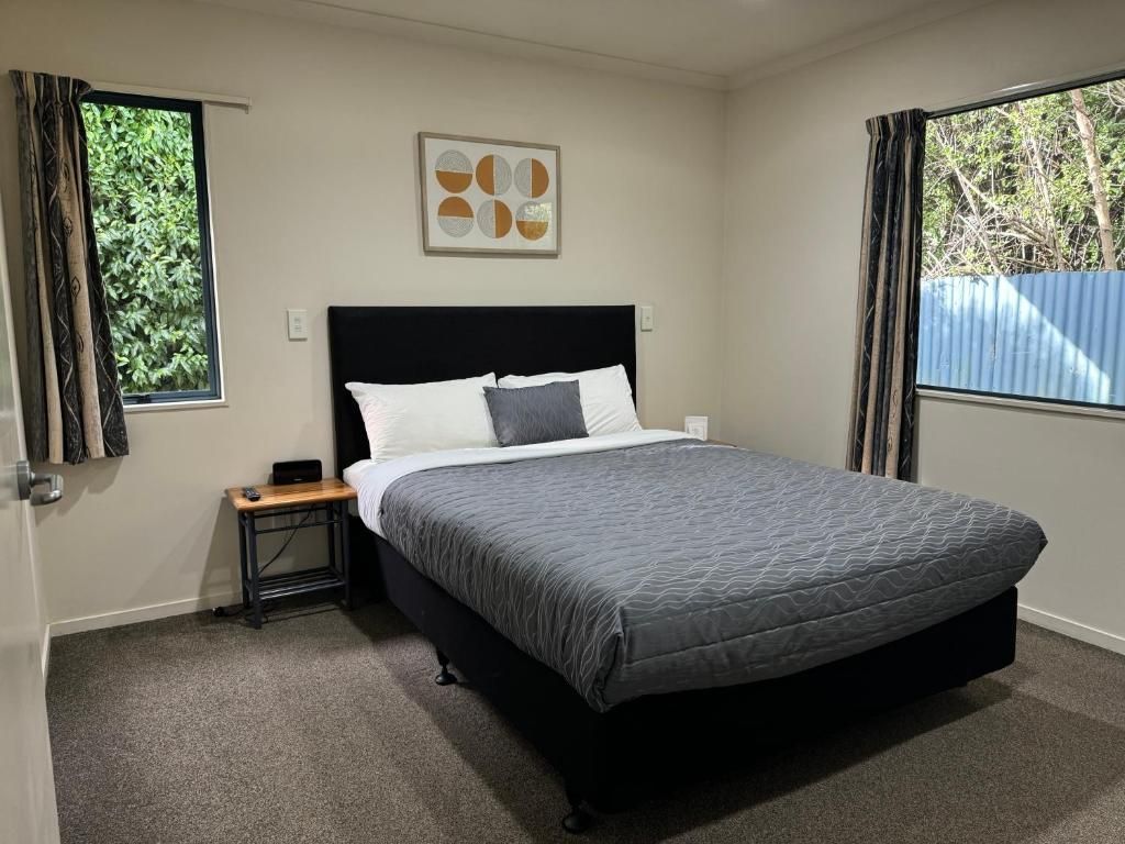 A bedroom with a king size bed and two windows.