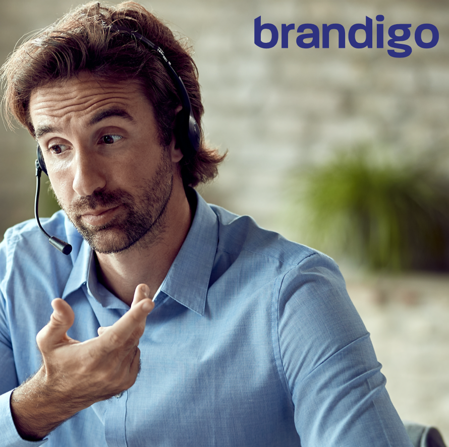 A man wearing a headset with the brandigo logo behind him