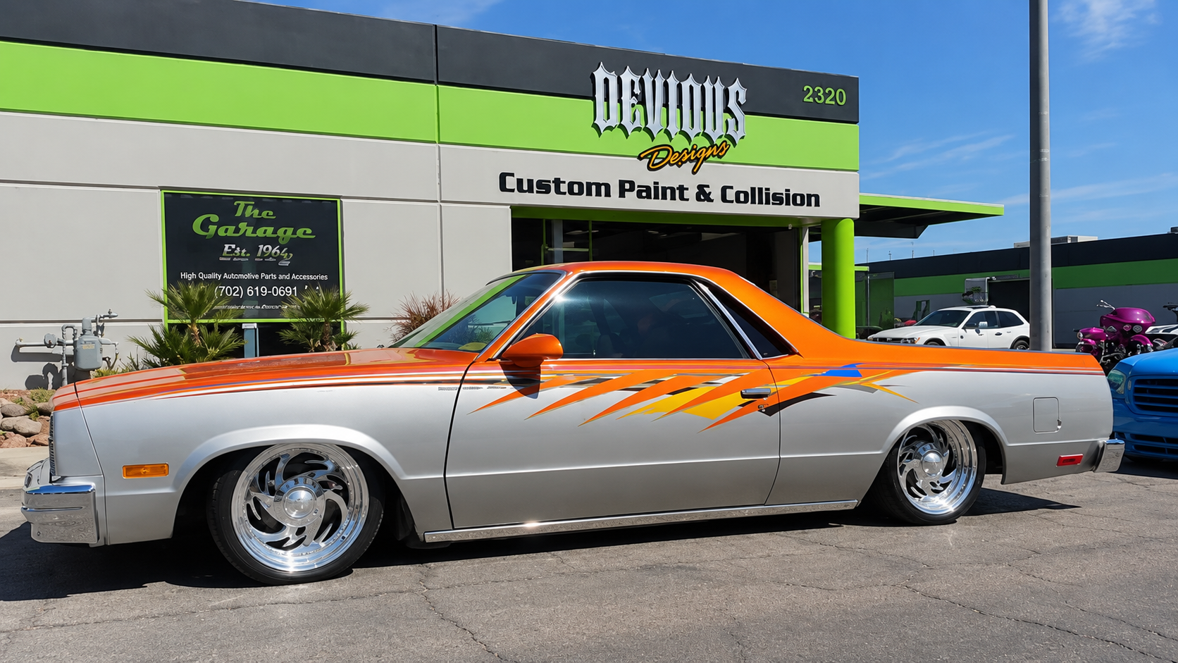 Custom silver car with orange flame decals parked outside a collision shop