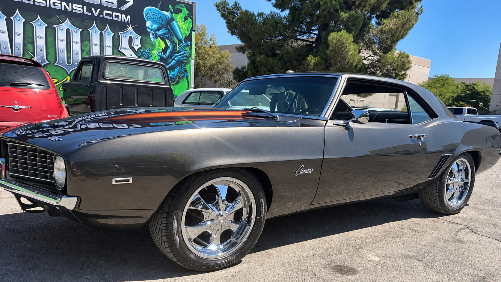 Classic dark gray Chevrolet Camaro parked outdoors on a sunny street, side view with chrome wheels