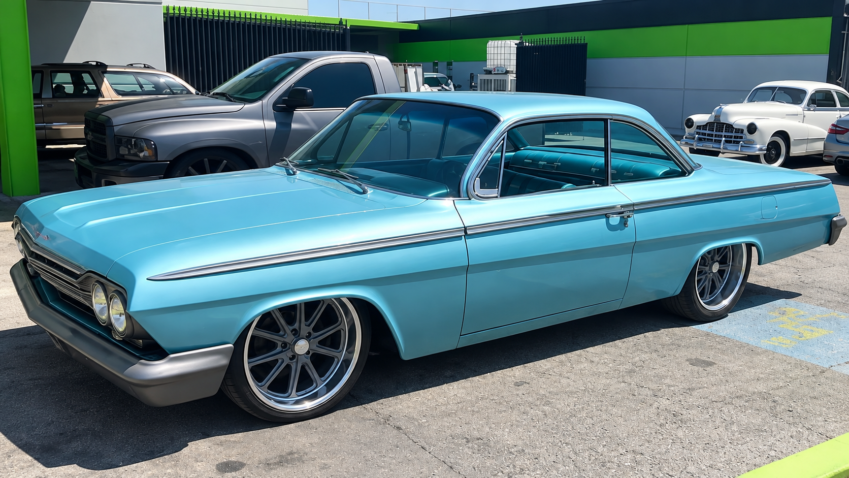 Turquoise vintage two-door car parked outdoors in bright sunlight