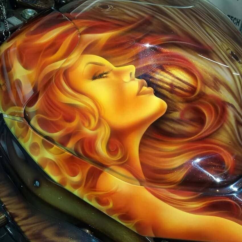 Abstract artwork of a golden woman’s face with flowing red-orange hair on a glossy dark background