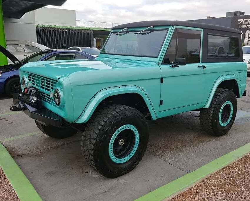 Turquoise vintage off-road SUV with black roof, parked outdoors