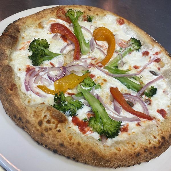 a pizza with broccoli peppers and onions on a white plate