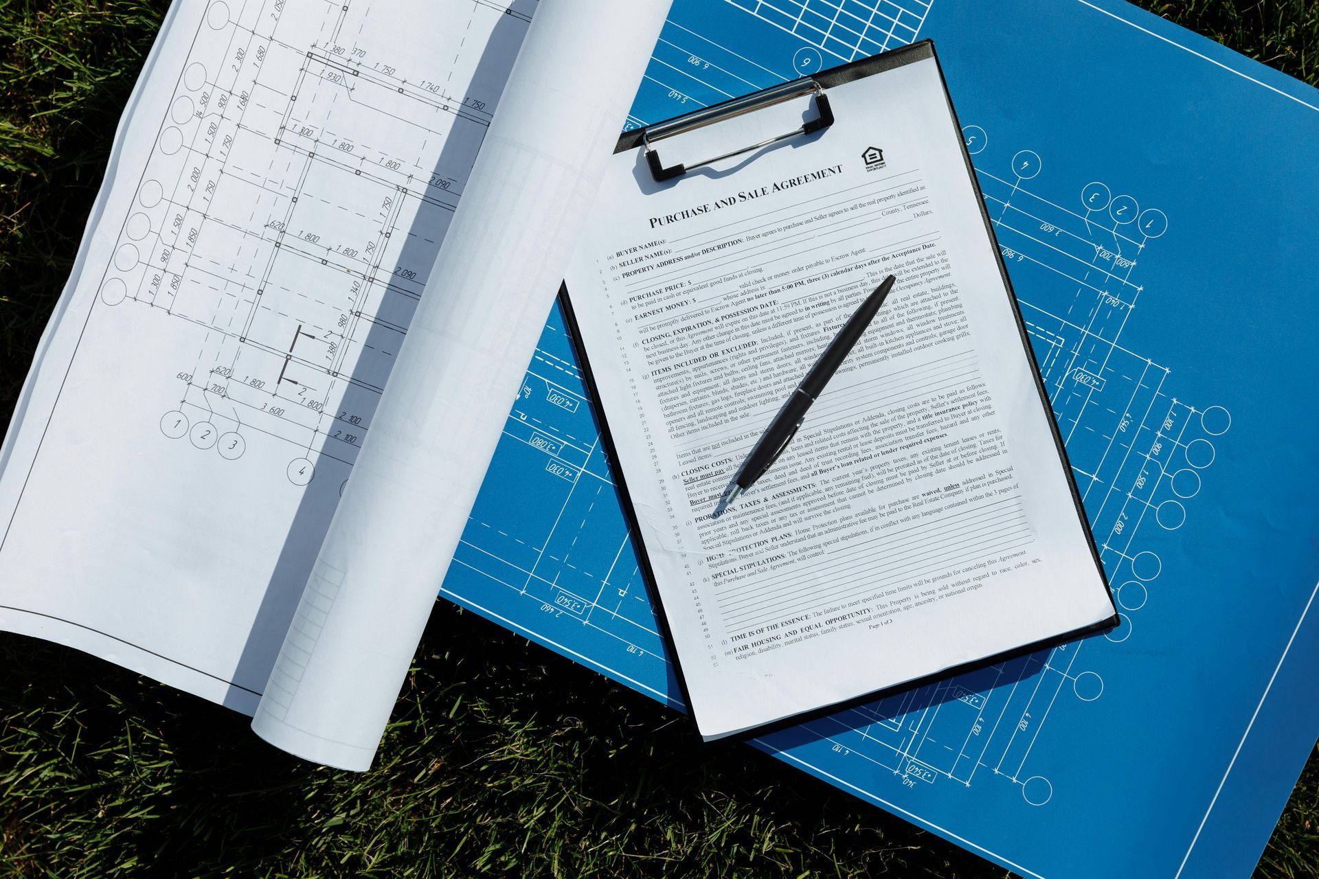 A clipboard with a pen on top of a blueprint