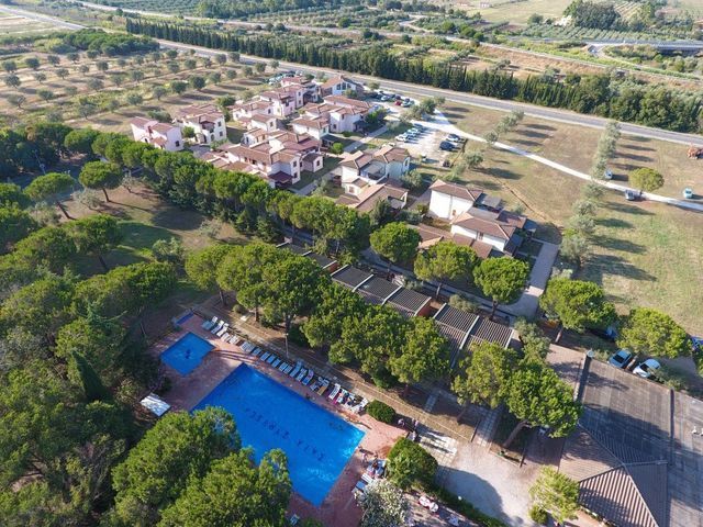 Vista aerea di una zona residenziale con piscina, alberi ed edifici, probabilmente un complesso turistico.
