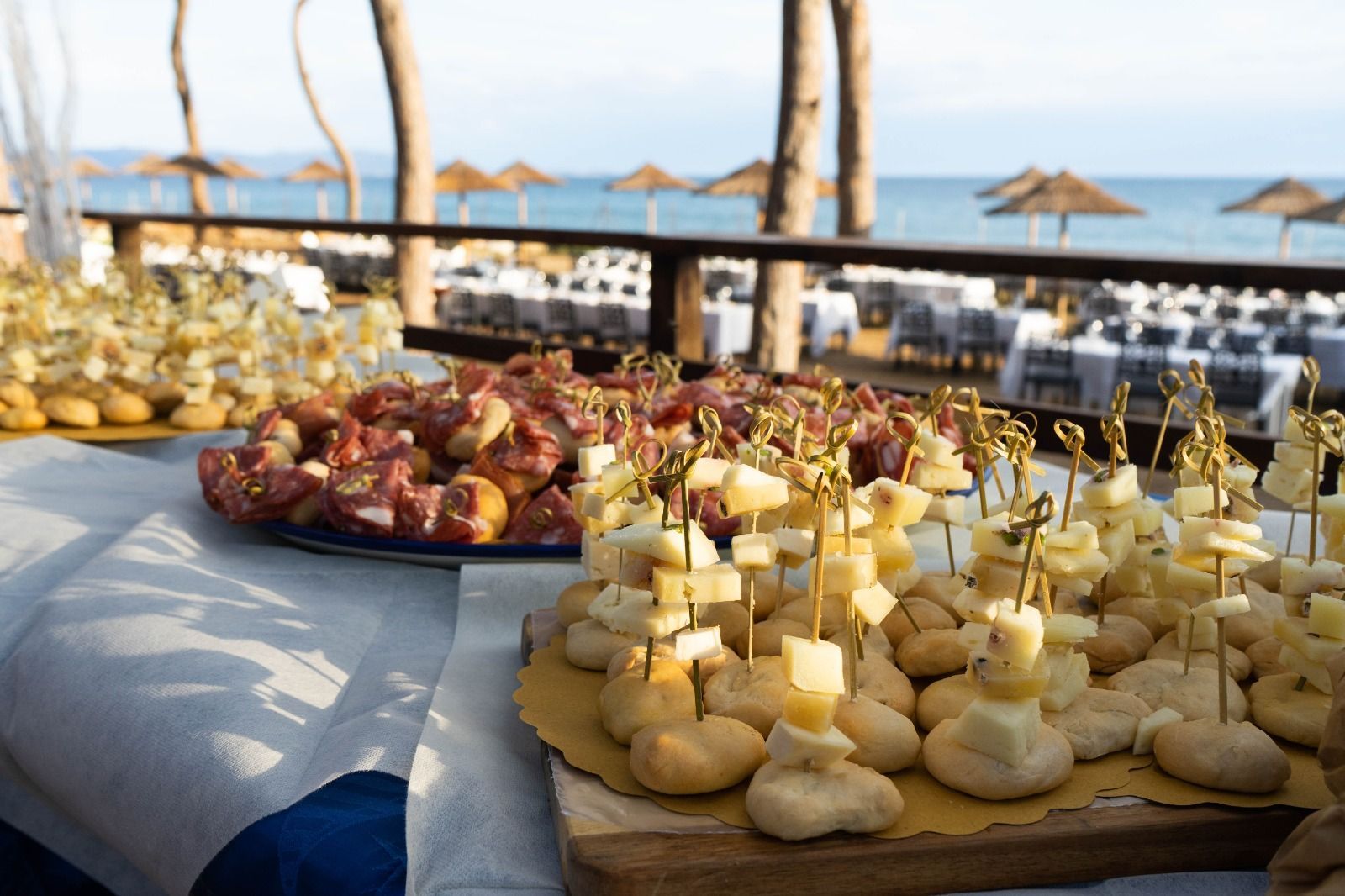 Antipasti su un tavolo con vista sull'oceano: cubetti di formaggio, salame e panini.