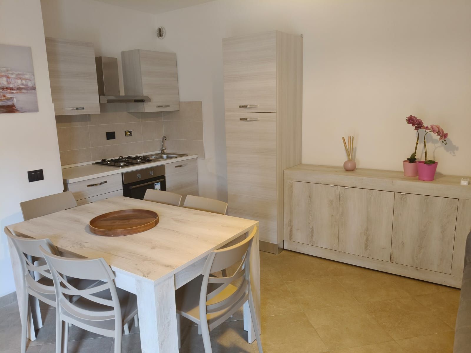 Cucina e zona pranzo con mobili in legno chiaro, tavolo e sedie.