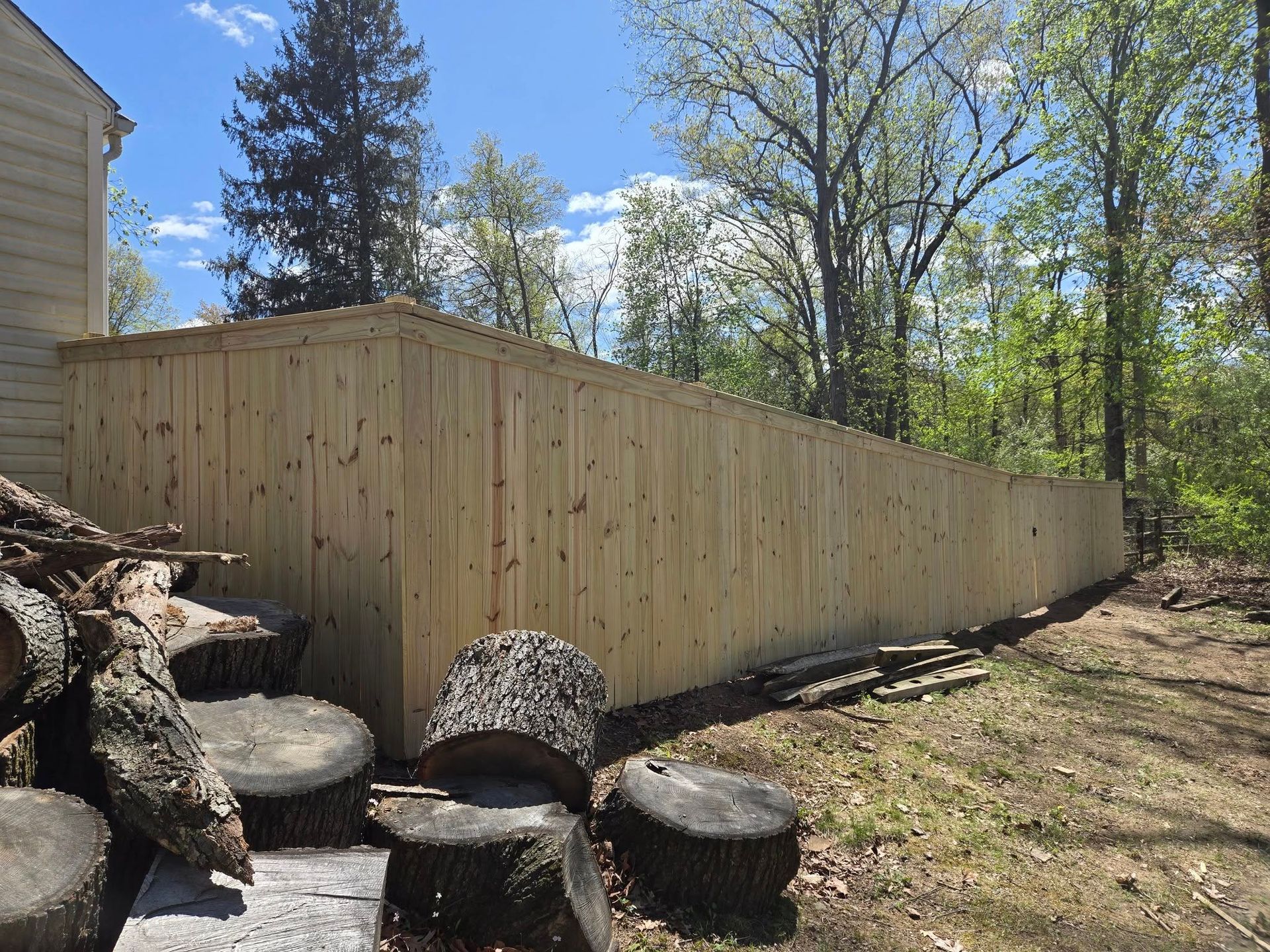 A wooden fence is surrounded by trees in a backyard.