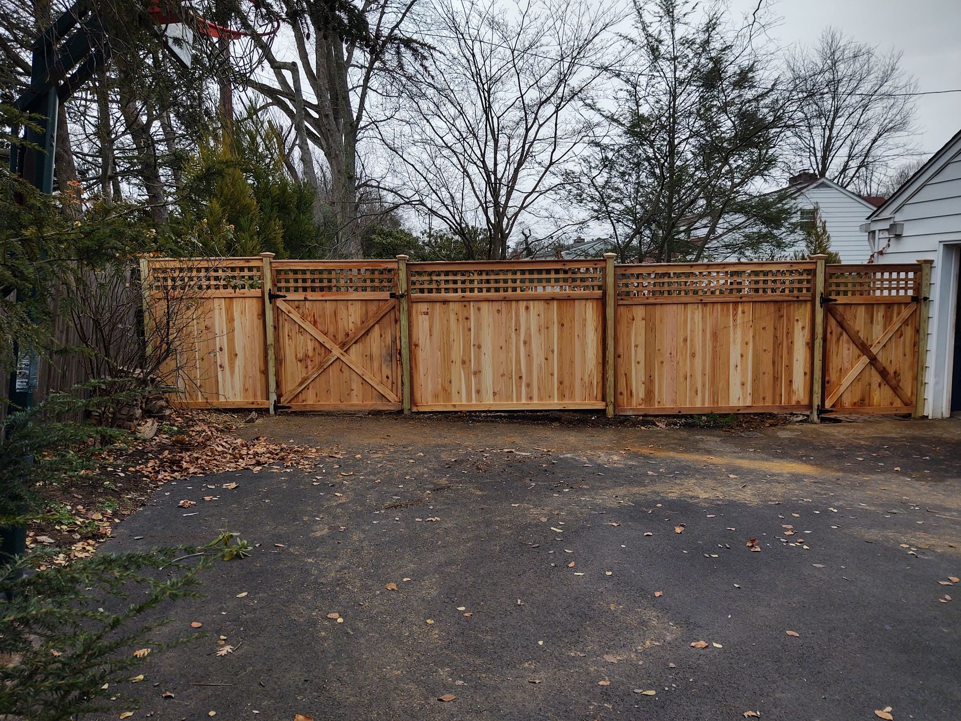 A wooden fence is sitting in the middle of a driveway next to a garage.