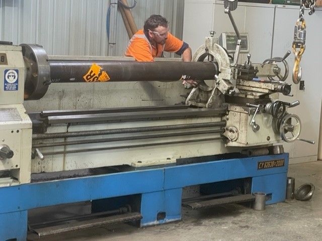 A man is working on a lathe in a factory.