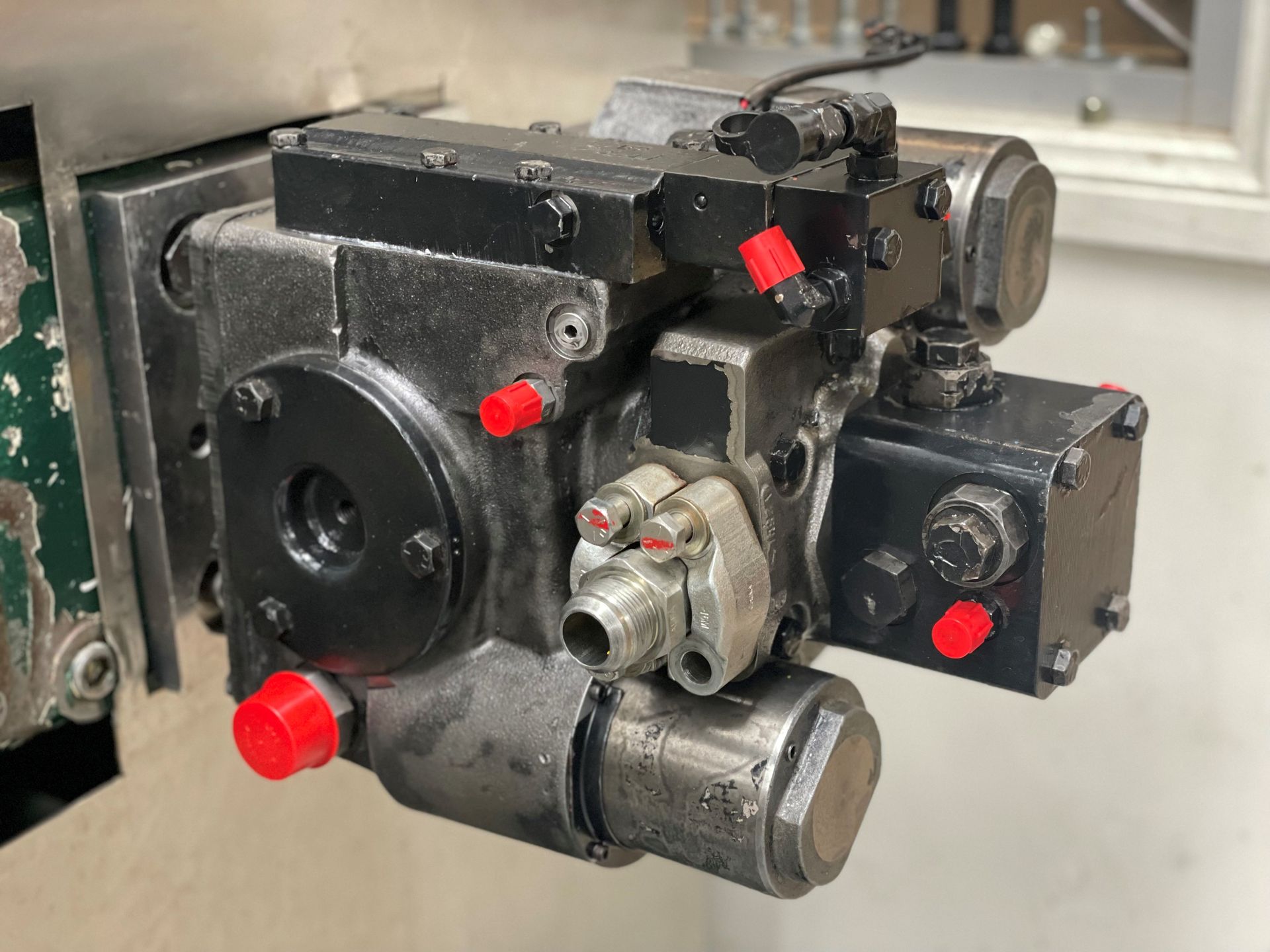 A close up of a hydraulic pump with red caps on it.