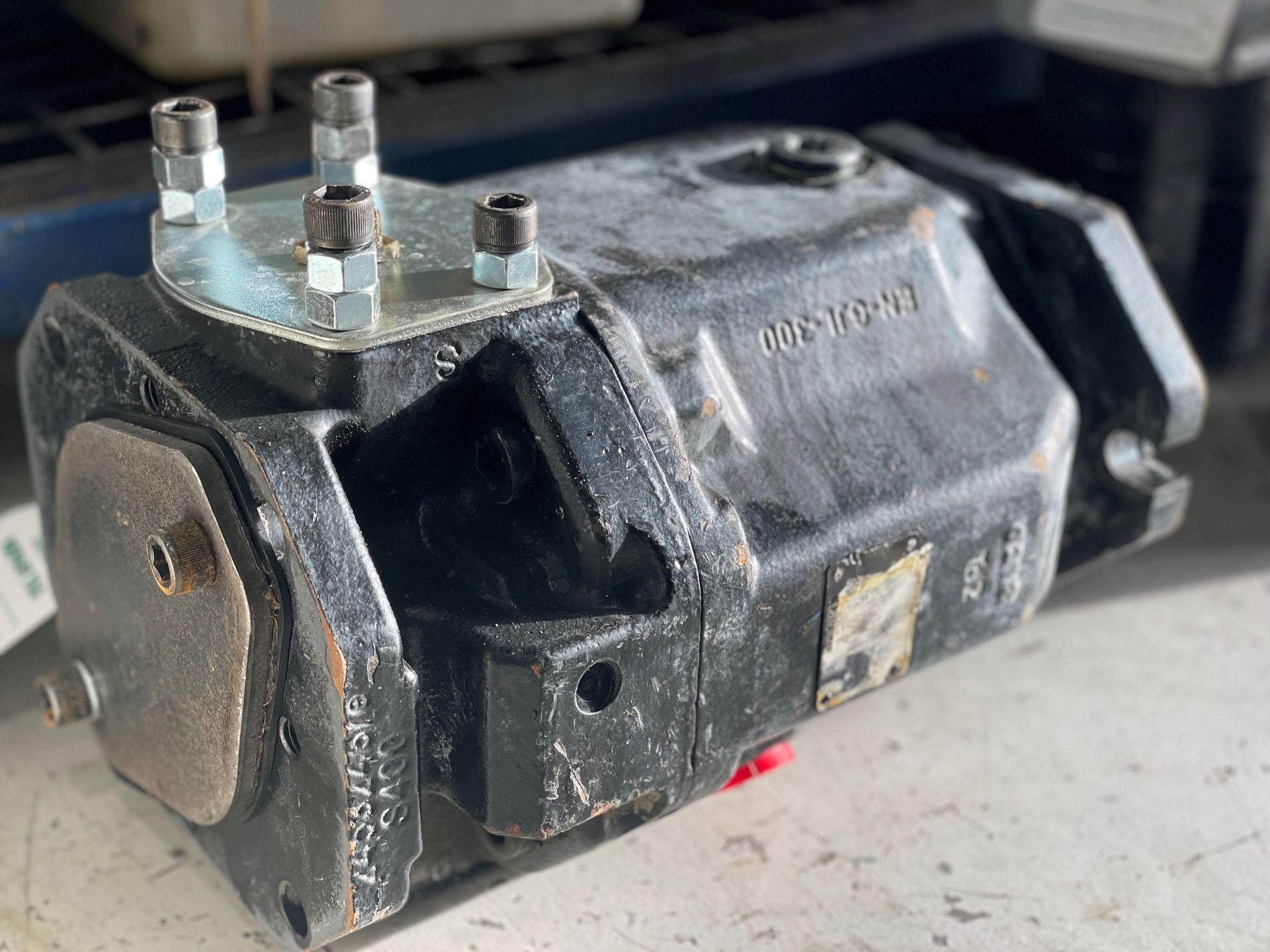 A black hydraulic pump is sitting on a white surface.