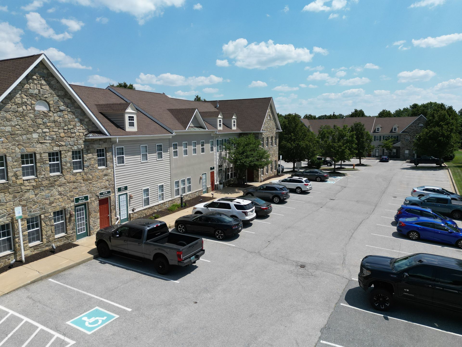 An aerial view of a parking lot with cars parked in front of a building.