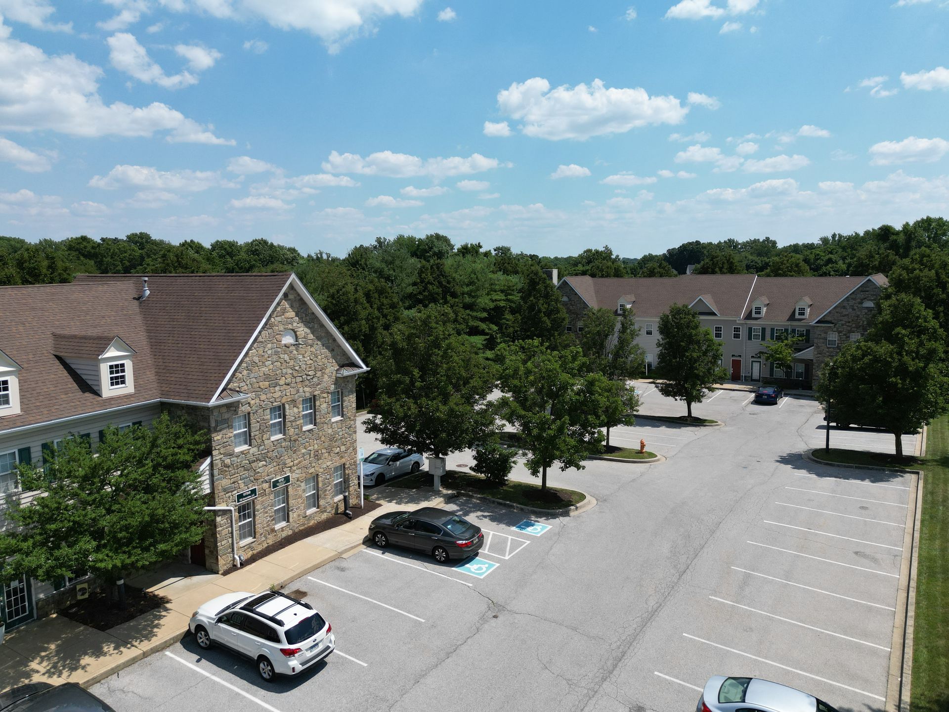 An aerial view of a parking lot with cars parked in front of a building.