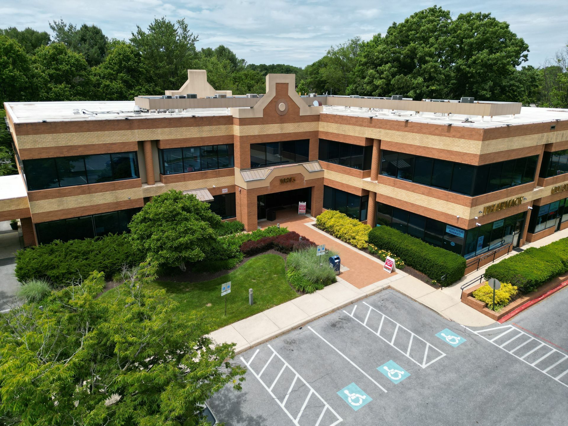 An aerial view of a large brick building with a parking lot in front of it.