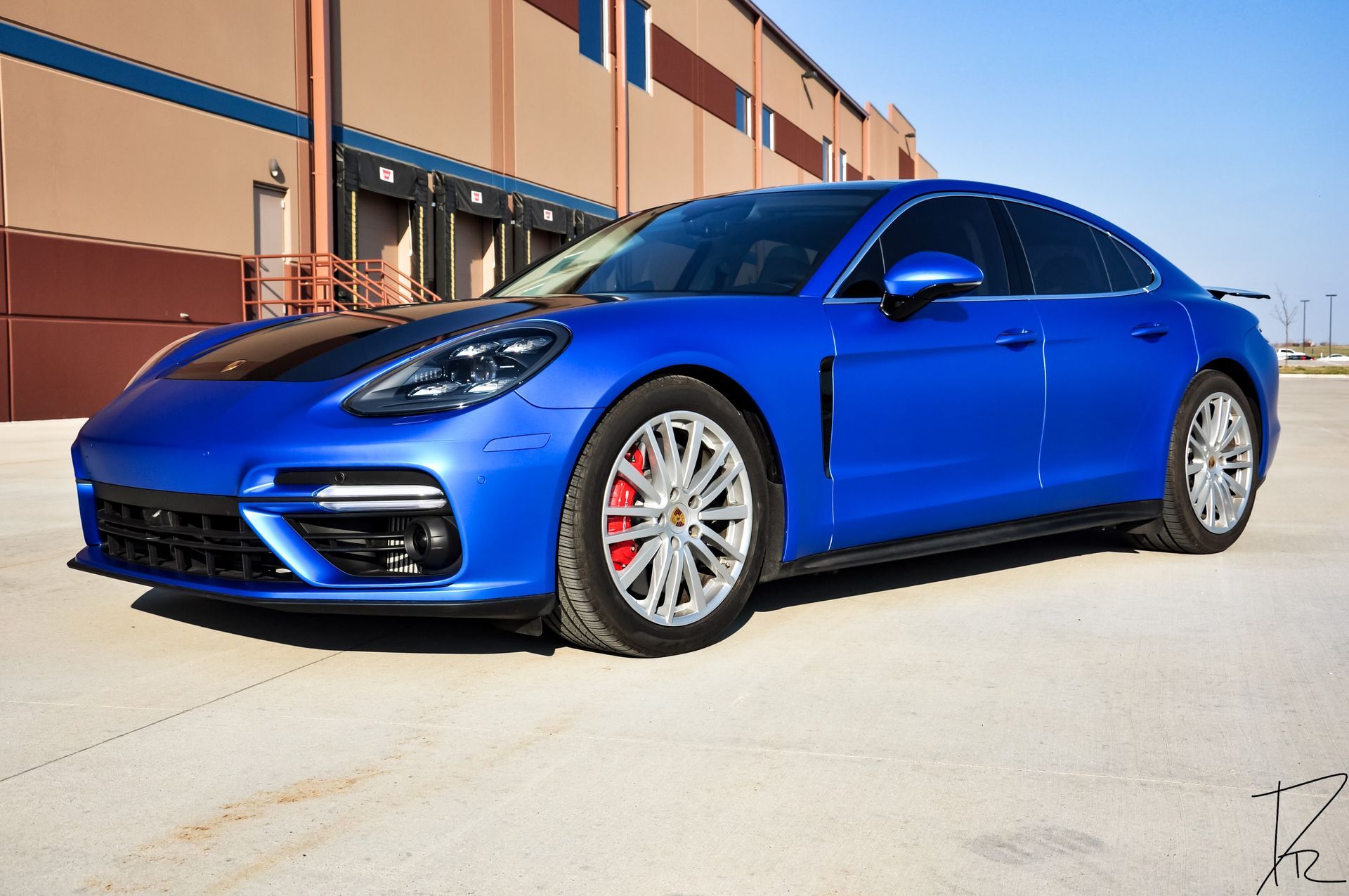 Blue Porsche sedan parked outside a building on a sunny day