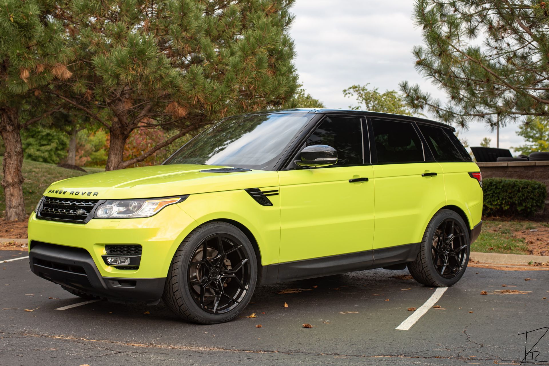 Bright lime green SUV parked on a driveway with trees and hedges in the background