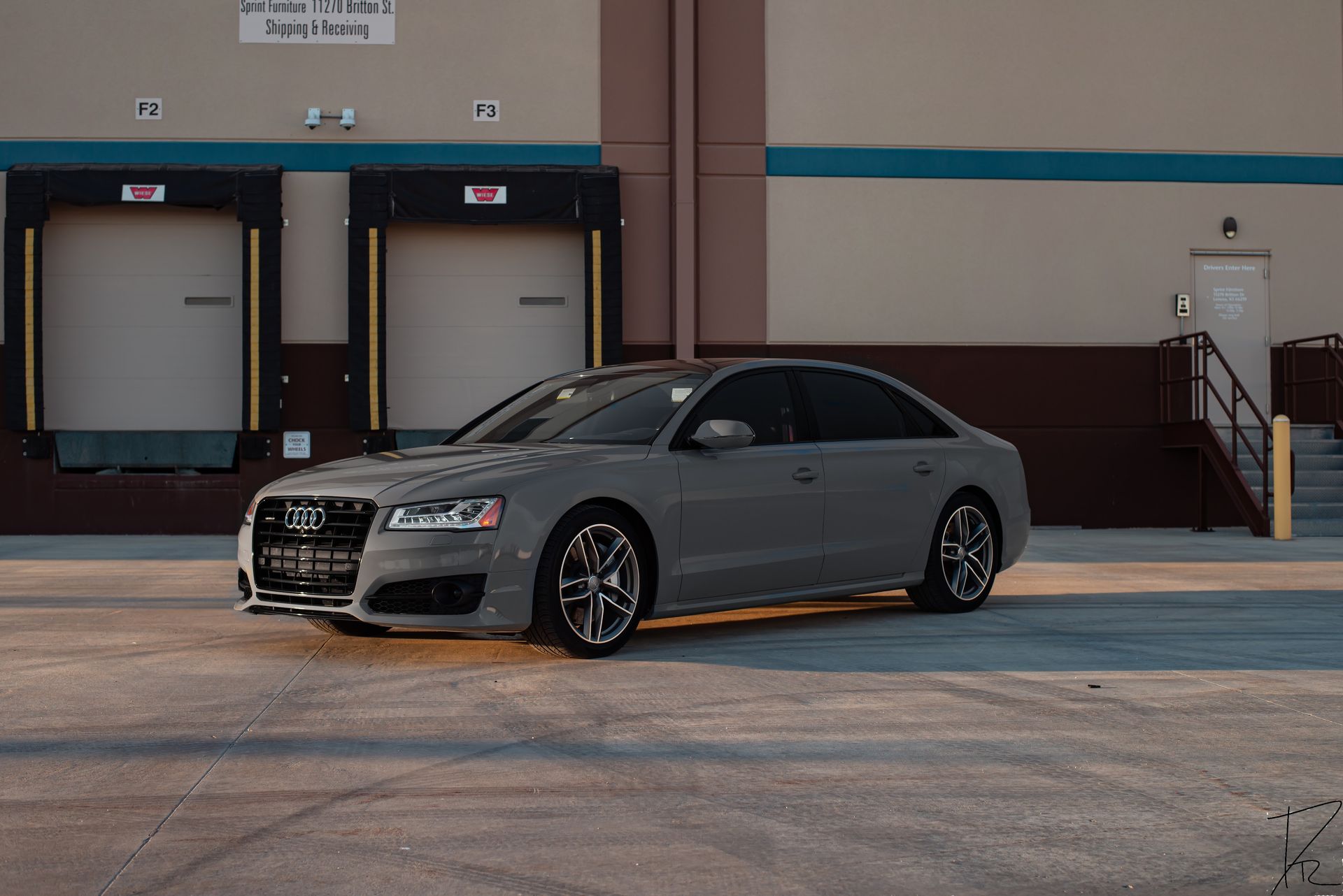 Silver sedan parked in front of warehouse loading docks