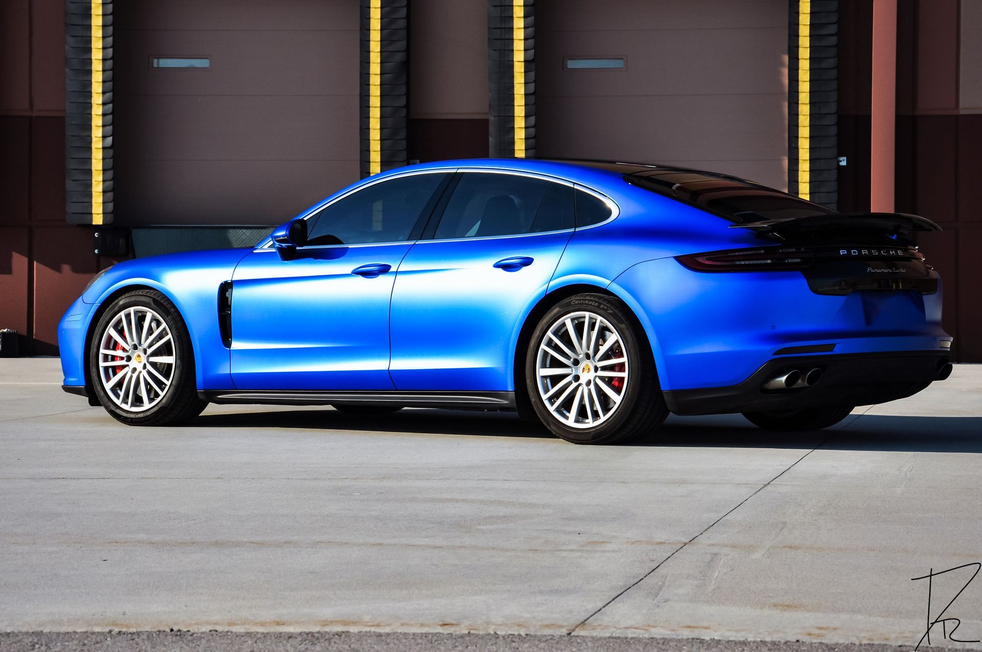 Blue electric sedan parked in front of a building with garage doors