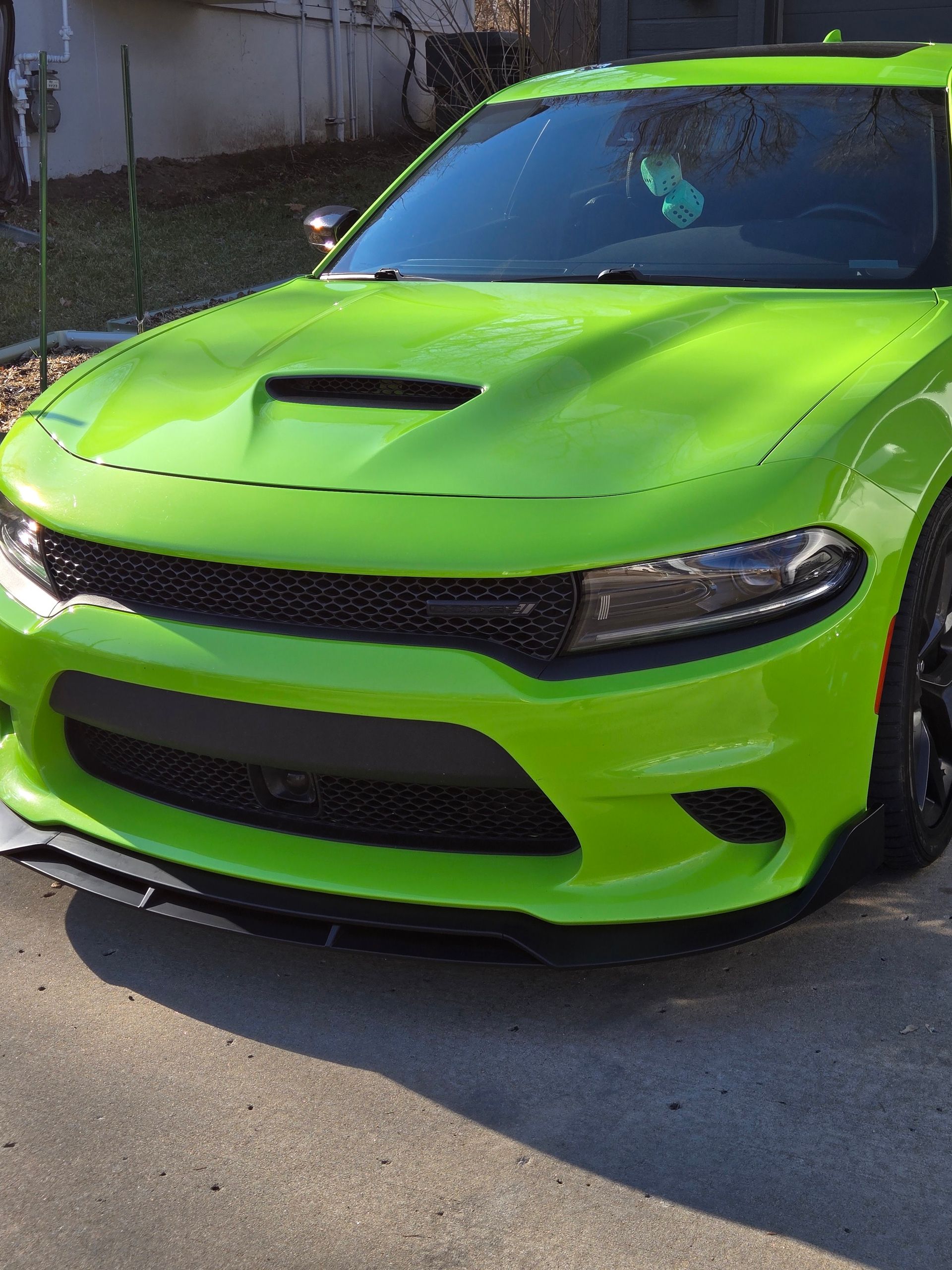 Bright green sports car parked outdoors, front view with a black grille and hood scoop.
