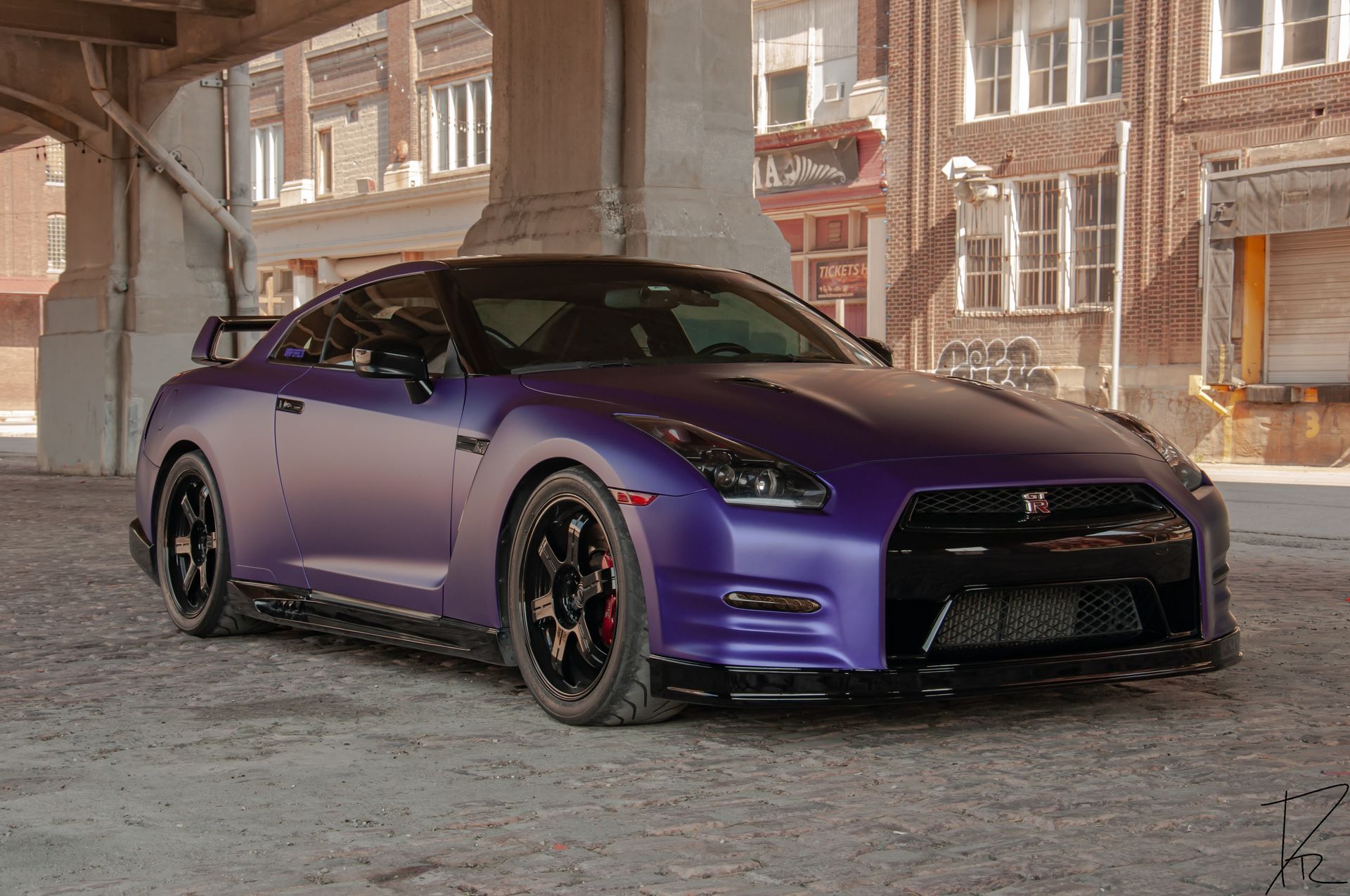 Purple sports car parked in an industrial alley, front three-quarter view