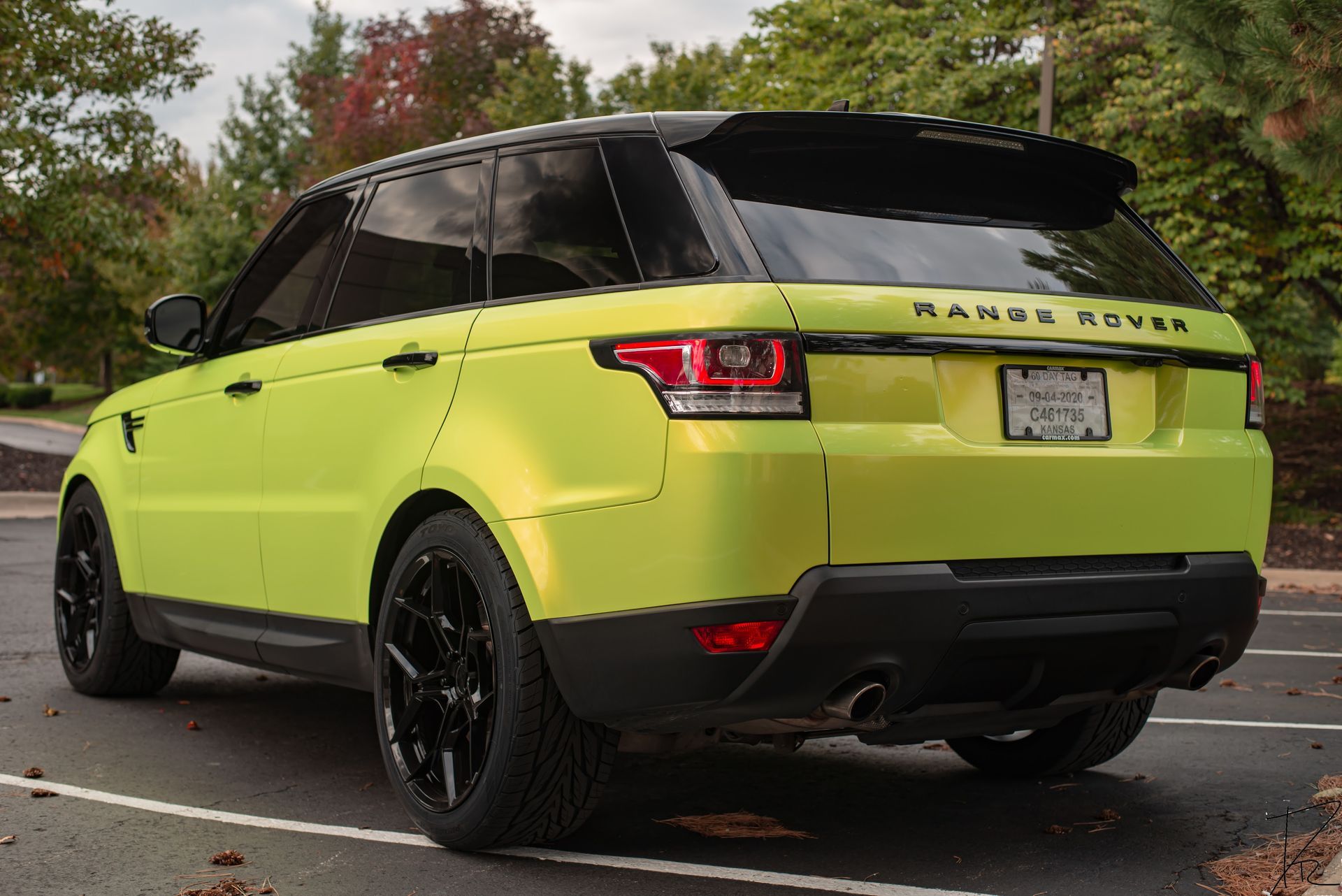 Bright lime green Range Rover SUV parked outdoors, rear three-quarter view on a wet road.