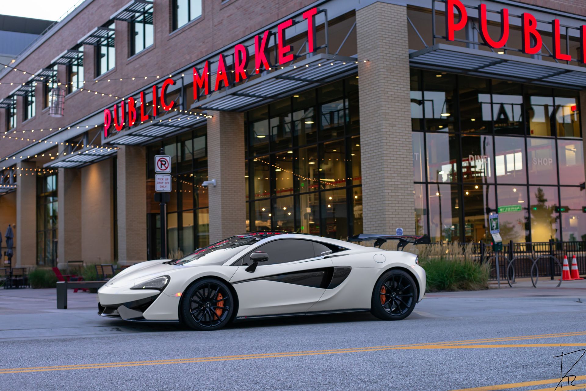 White sports car parked outside a Public Market building at dusk