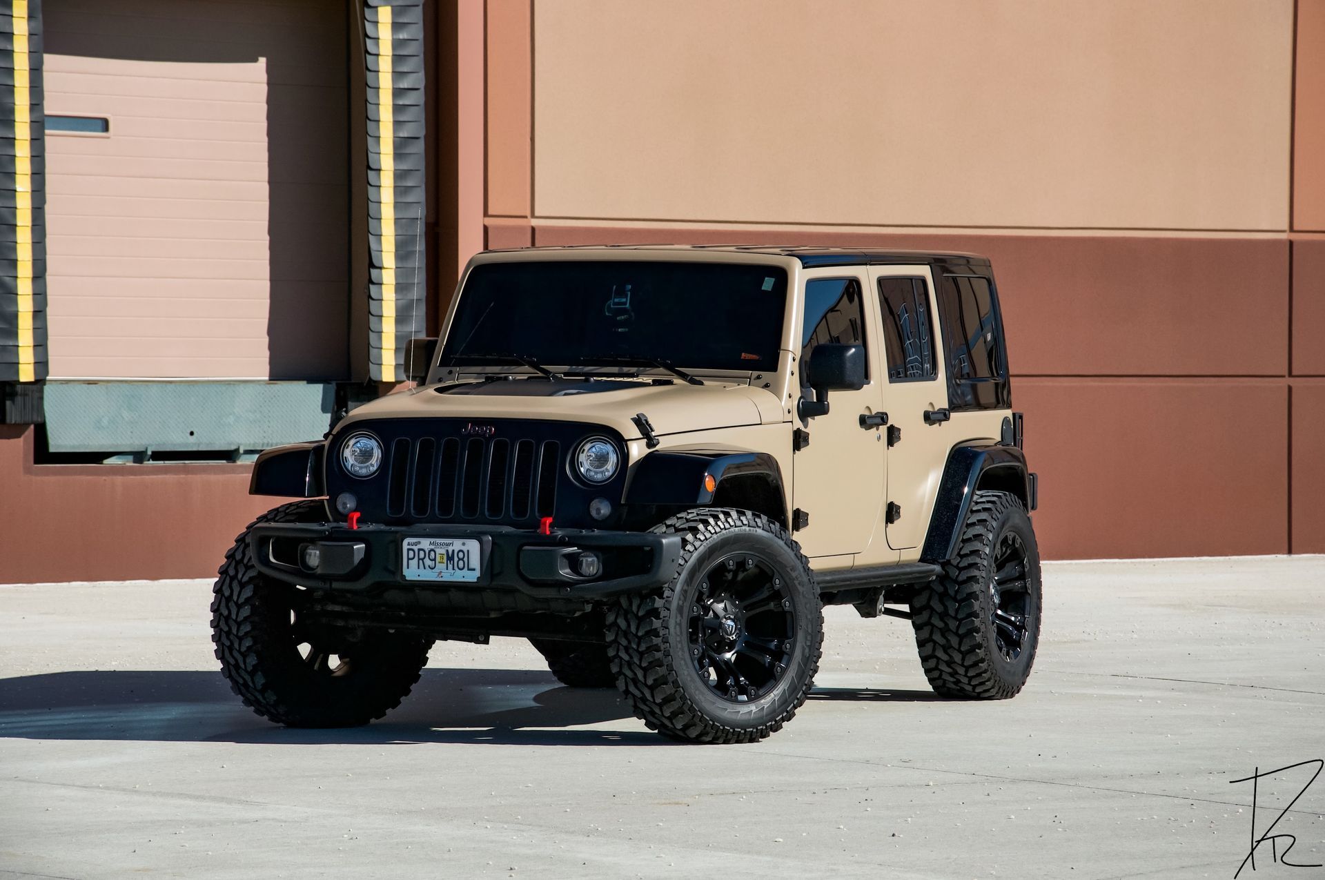 Black-and-tan Jeep Wrangler parked in front of a building on a sunny day