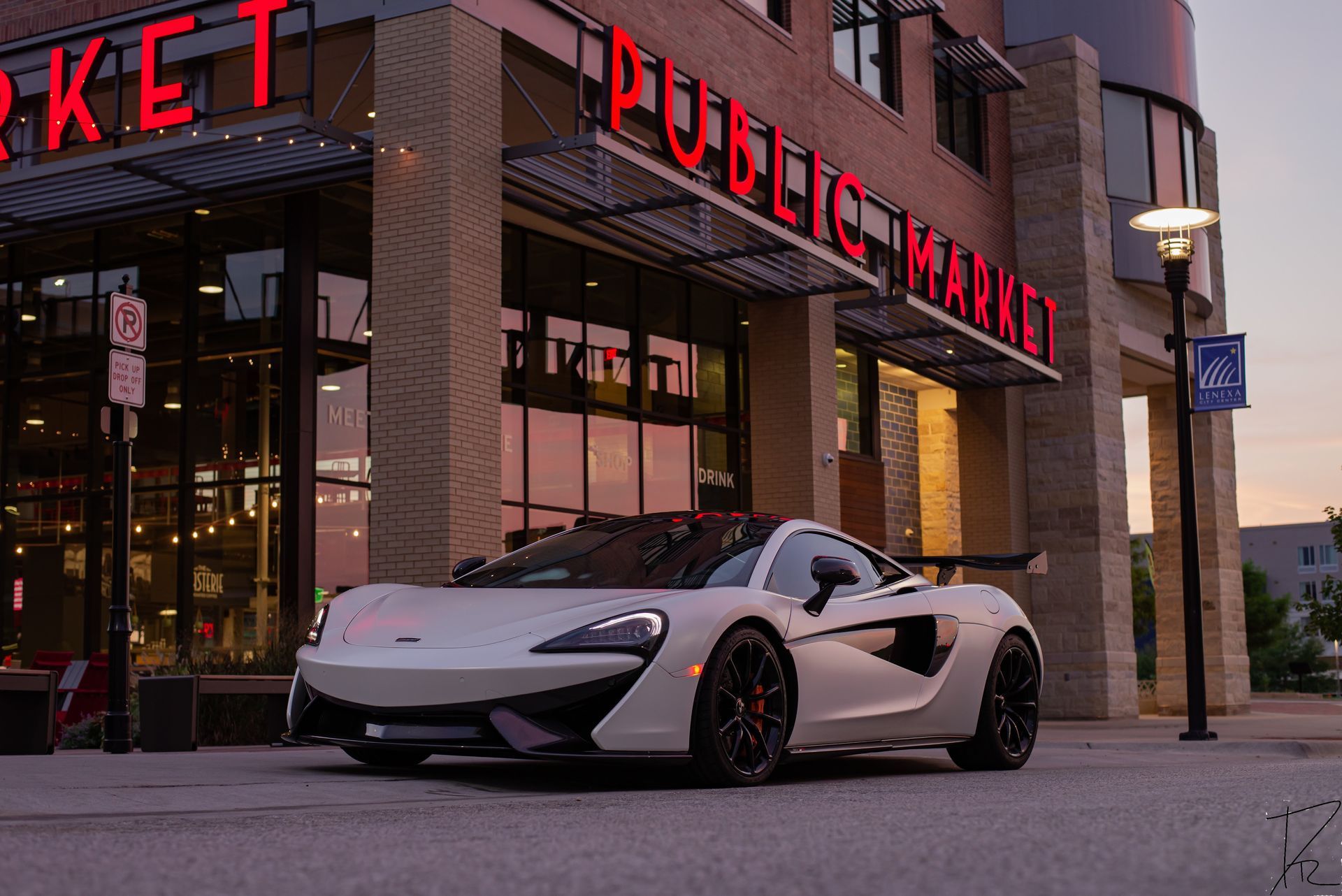 White sports car parked outside a Public Market building at dusk