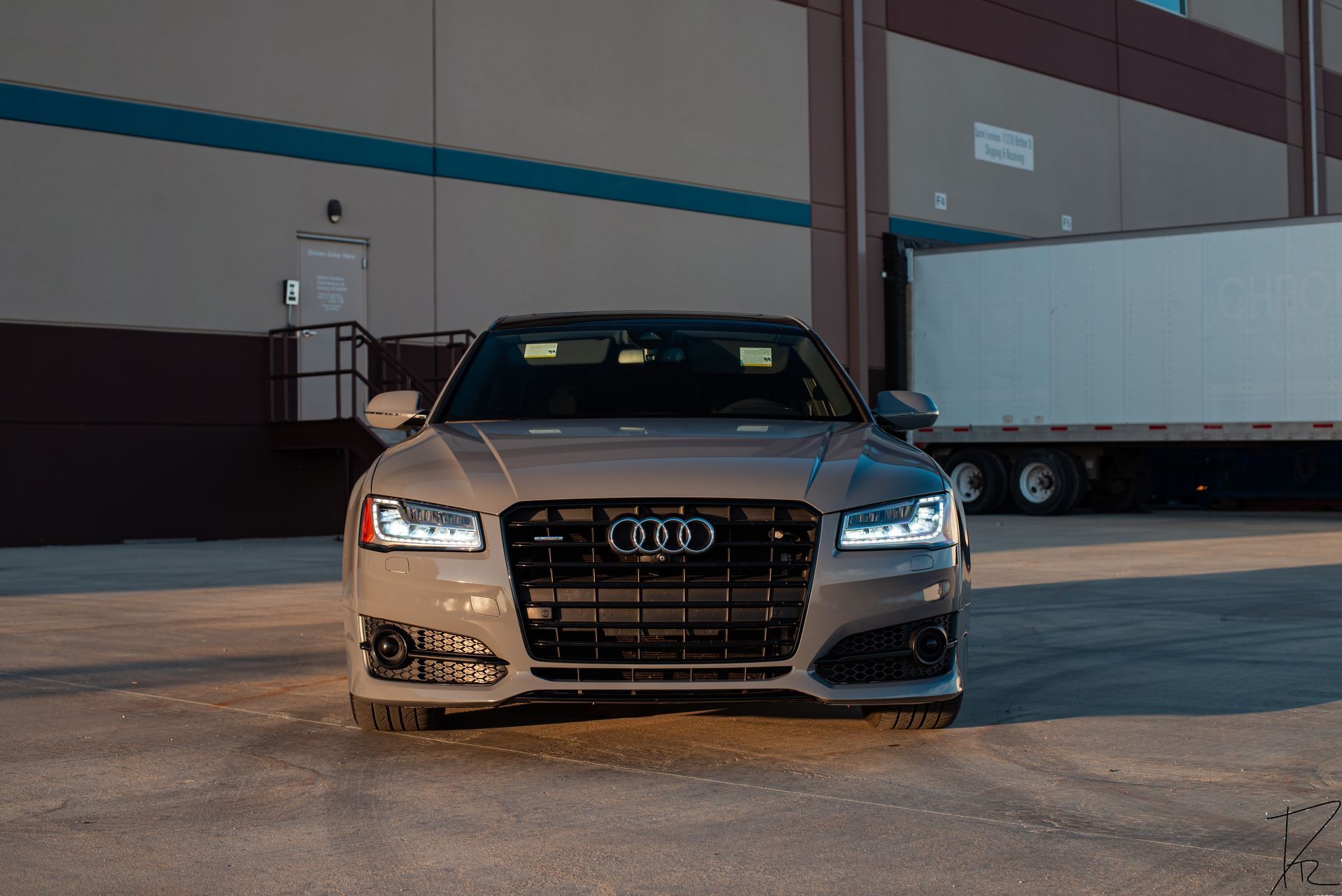 Silver Audi sedan parked in an industrial lot, front view at dusk.