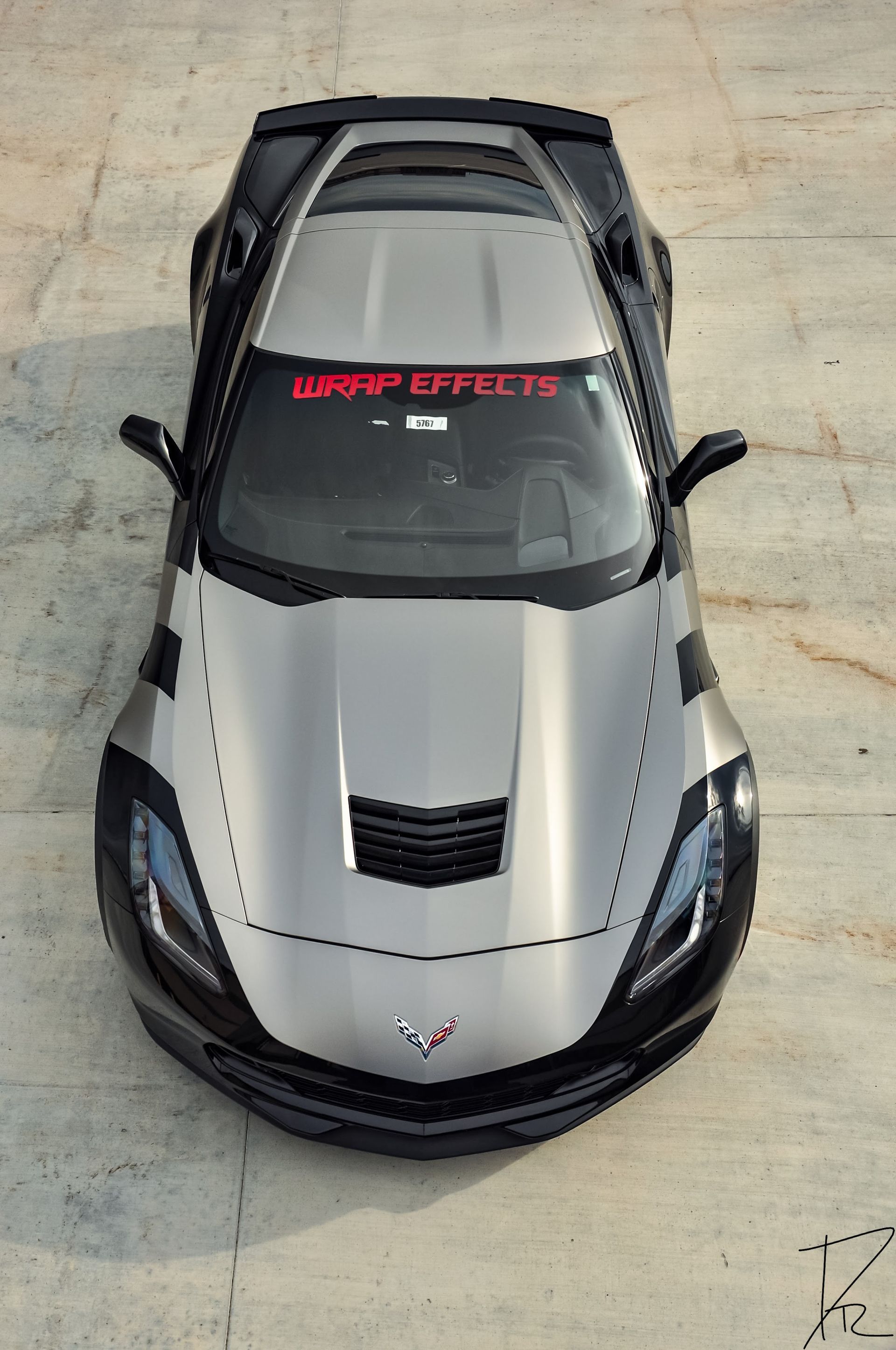 Silver sports car with black accents, viewed from above on a concrete surface