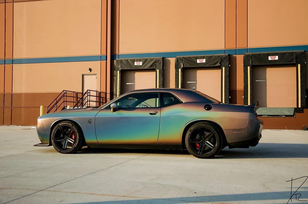 Rainbow-gradient sports car parked outside a warehouse loading dock