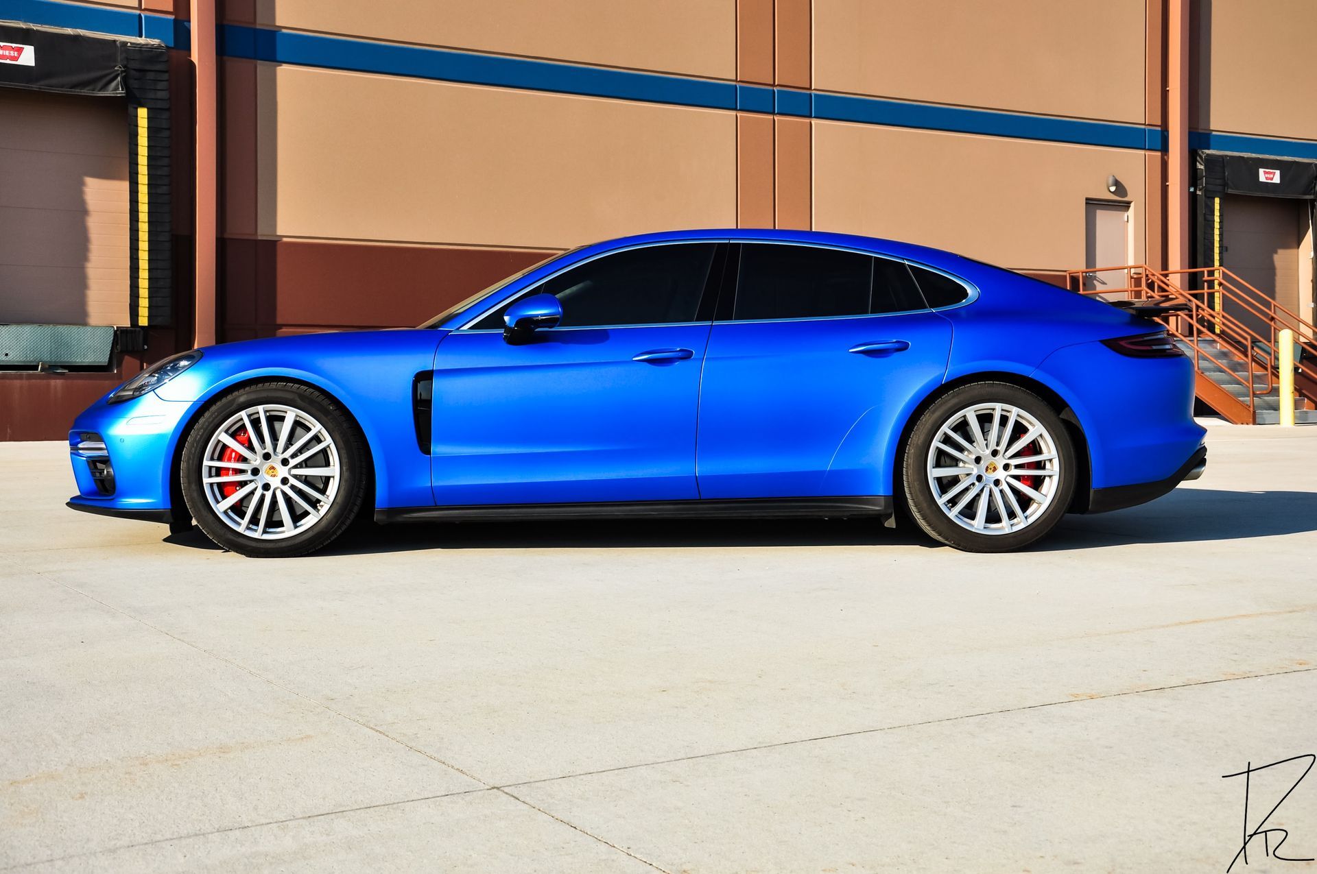 Blue sports coupe parked outside a building in bright sunlight