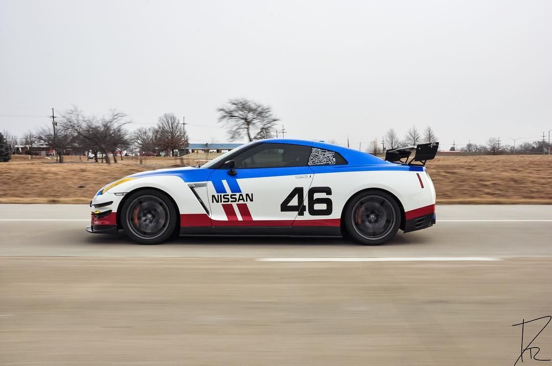 Blue and white race car number 46 speeding on a track with desert scenery